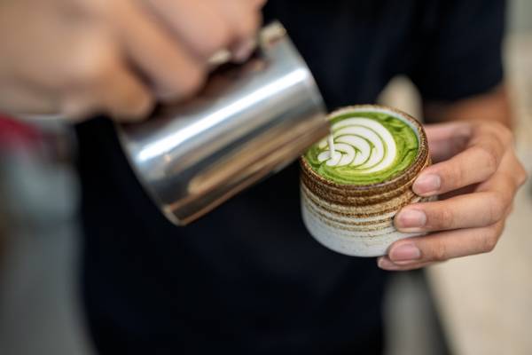 barista pouring a matcha latte