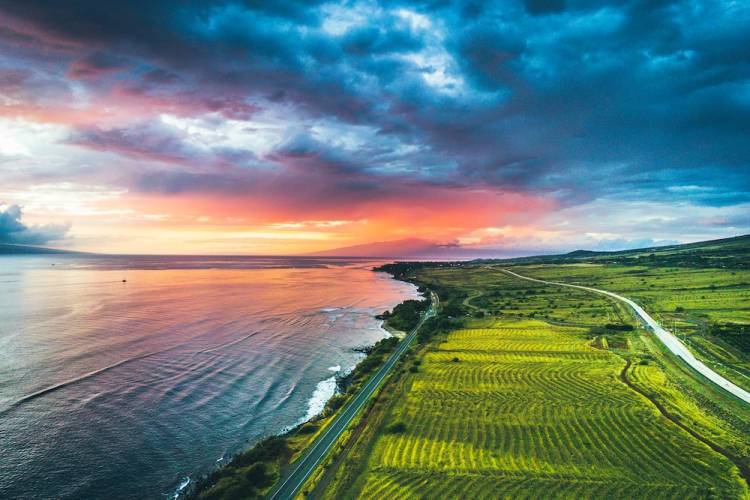 Aerial view showing stunning sunset over the water and farmland in Maui