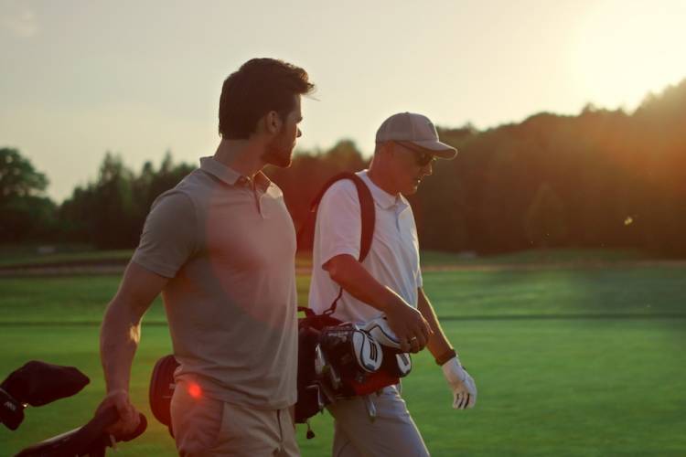two men on a golf course at sunset