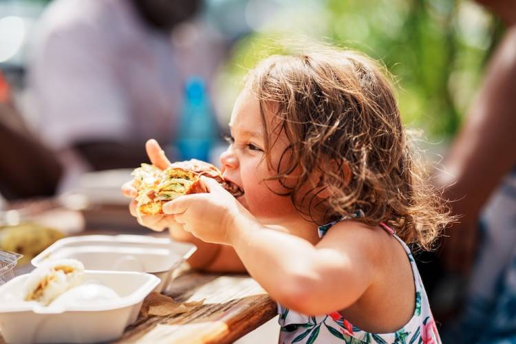 little kid eating food outside on a sunny day in hawaii