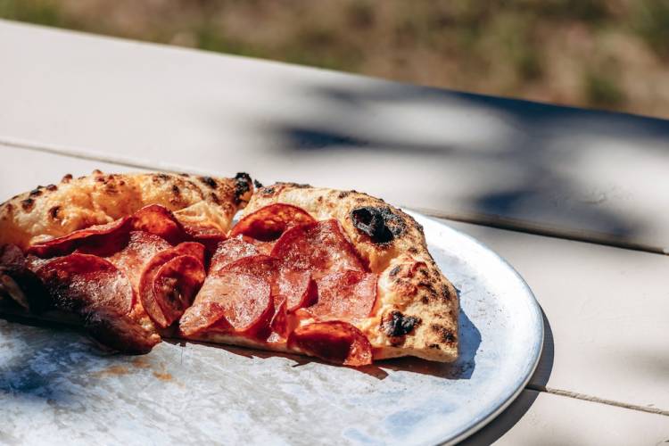 half a pepperoni pizza on a picnic table