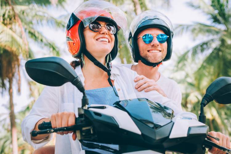 couple on a scooter with palm trees in background