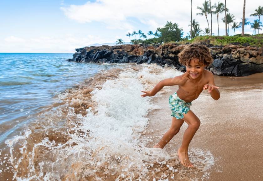 child playing in water on the beach in Maui
