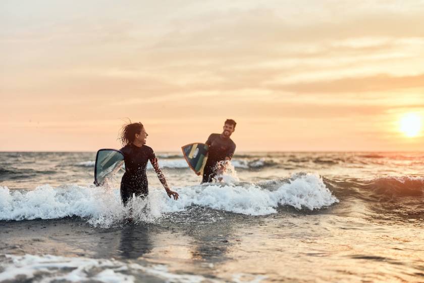 couple running in the waves with their surfboards in tow