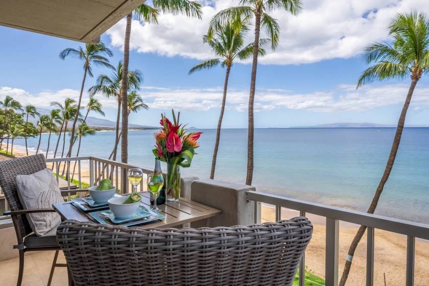 covered lanai featuring a table with beautiful flowers and glsses of wine overlooking beach